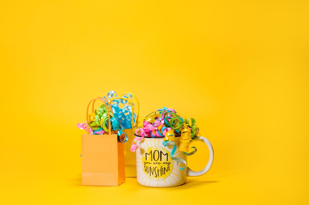 Cheerful mug with colorful ribbons, perfect for Mother's Day gifts on a bright yellow background.